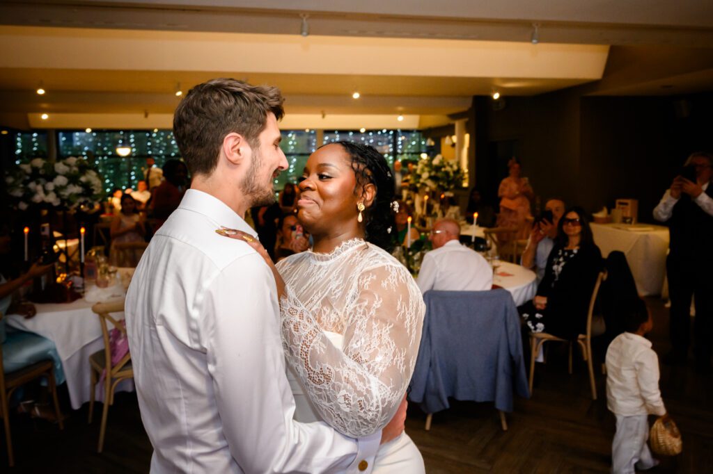 The bride and groom sharing their first dance in the Merchant Room at The Castlefield Rooms, with guests watching from their seats in the background.