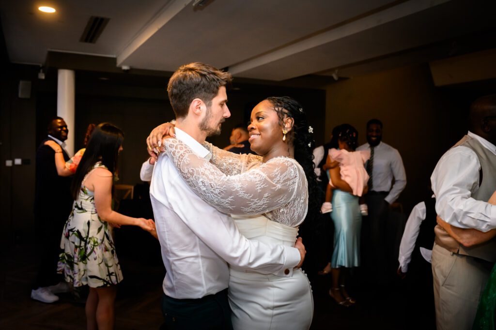 The bride and groom dancing together on the dance floor in the Merchant Room at The Castlefield Rooms during the evening reception, with other guests dancing around them.