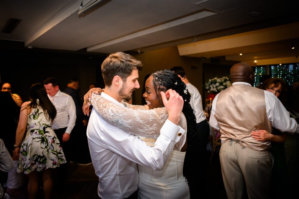 The bride and groom dancing together on the dance floor in the Merchant Room at The Castlefield Rooms, the bride smiling up at the groom during the evening reception.