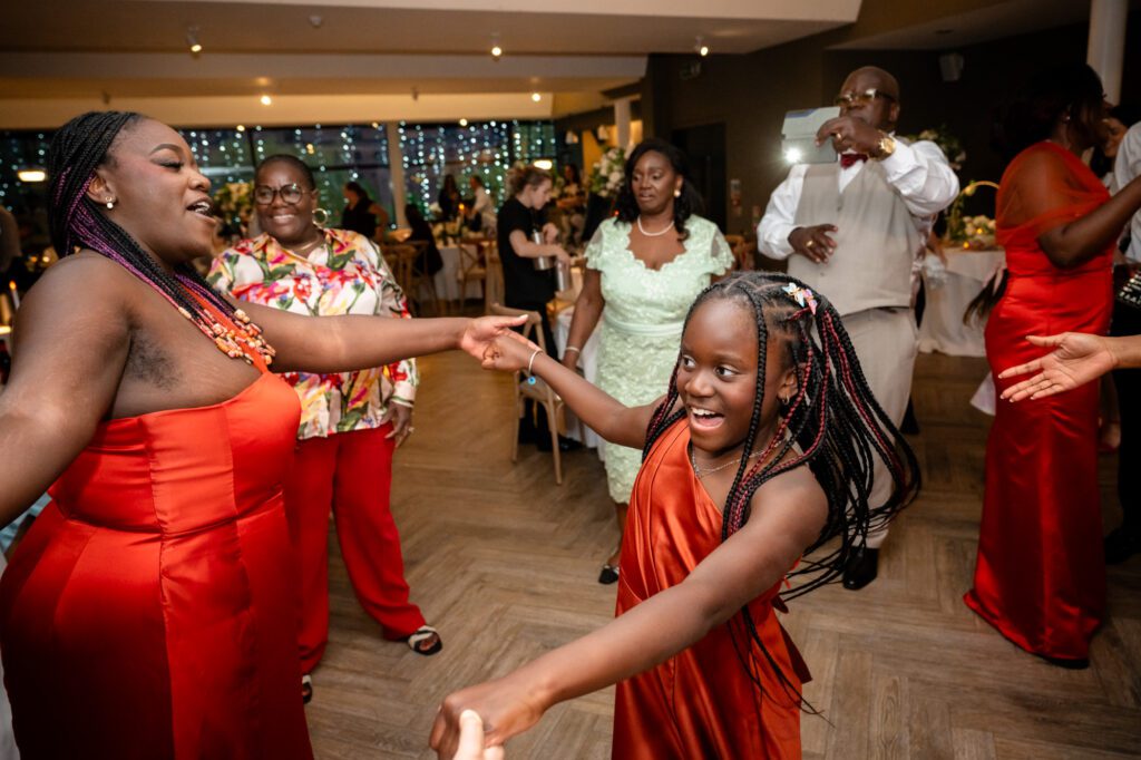 Wedding guests dancing on the dance floor at The Castlefield Rooms during the evening reception, including a young girl in a red dress being spun around.