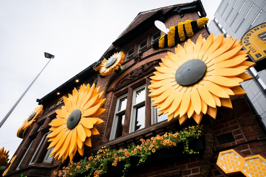 Close-up of oversized sunflower sculptures on the brick exterior of the Black Friar pub in Salford