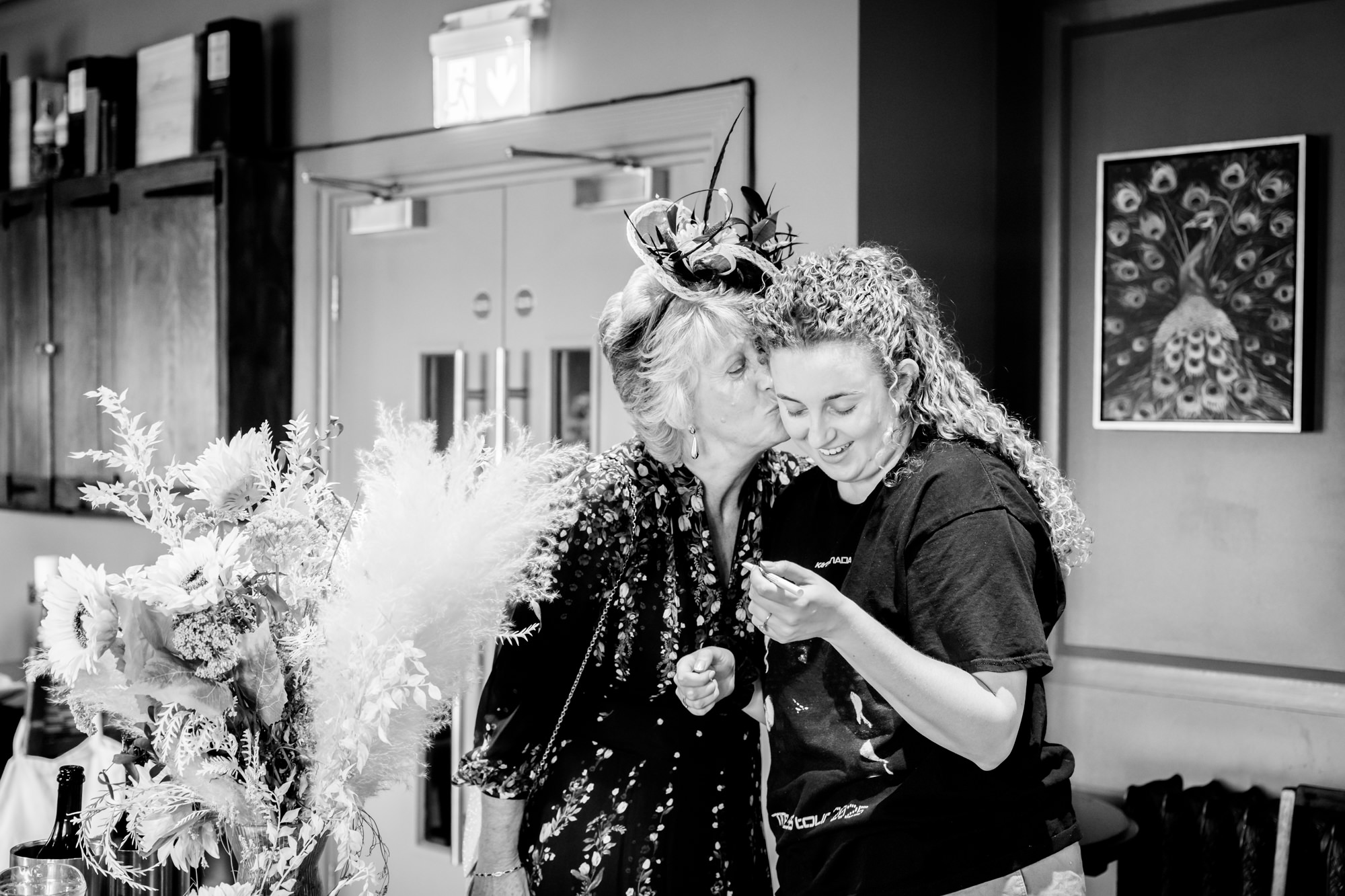 Mother of the bride kissing the bride on the cheek while getting ready, black and white