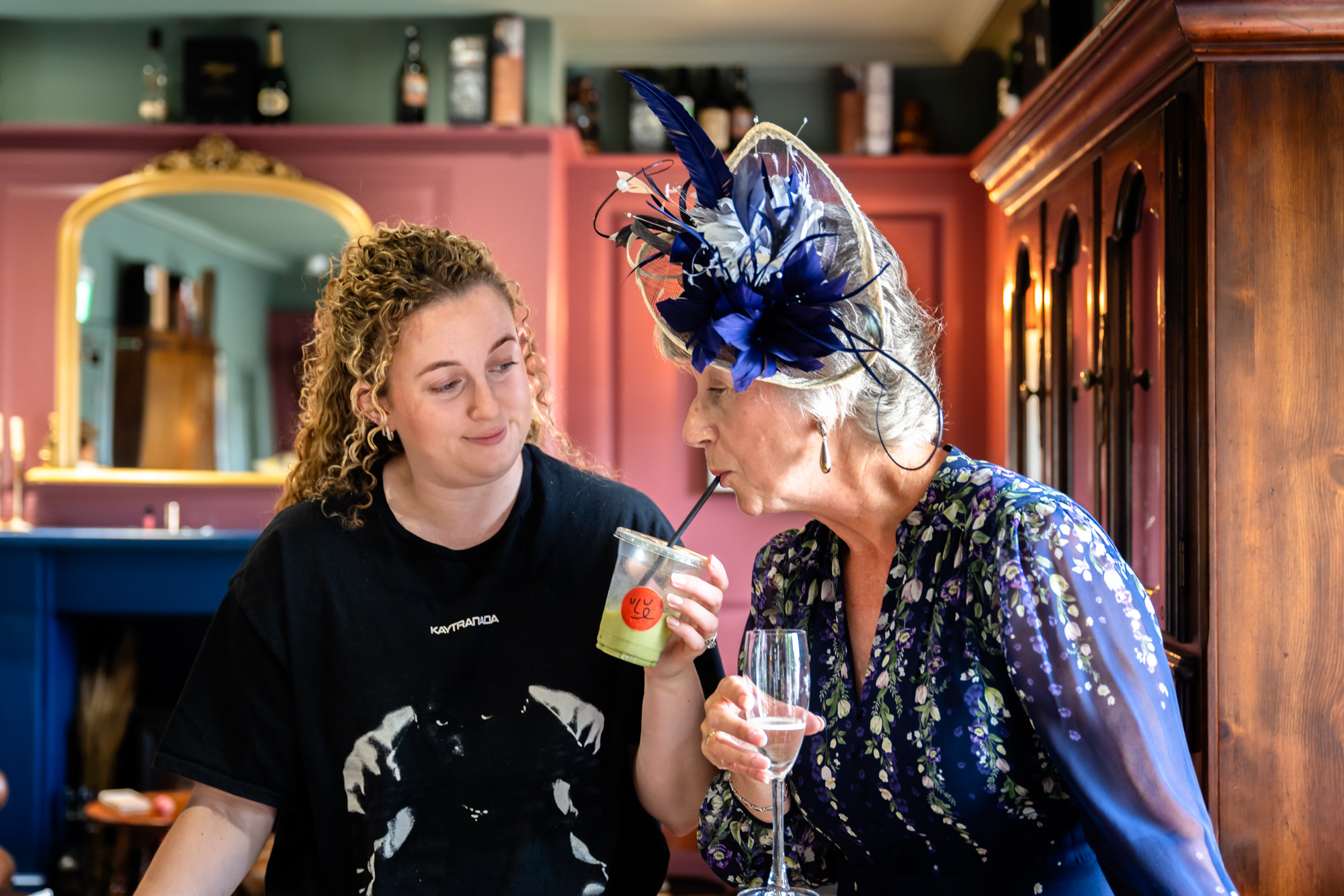 Mother of the bride sipping a drink from the bride's cup while getting ready
