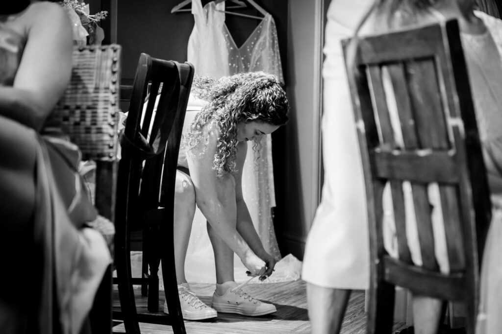 Bride lacing up her white trainers ahead of the ceremony, black and white