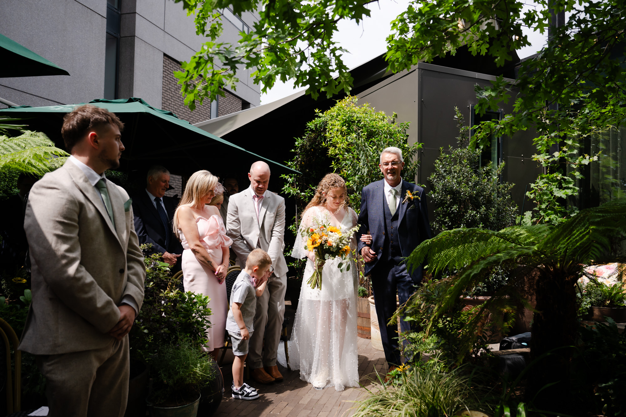 Bride walking down the aisle towards her ceremony at the Black Friar Salford, guests looking on