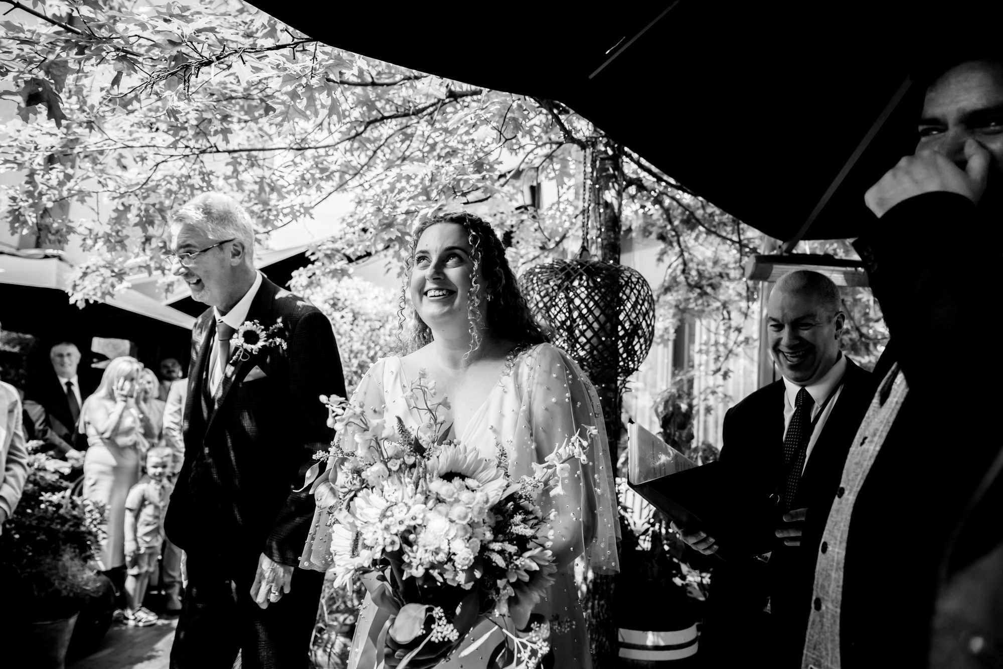 Bride walking down the aisle smiling, black and white