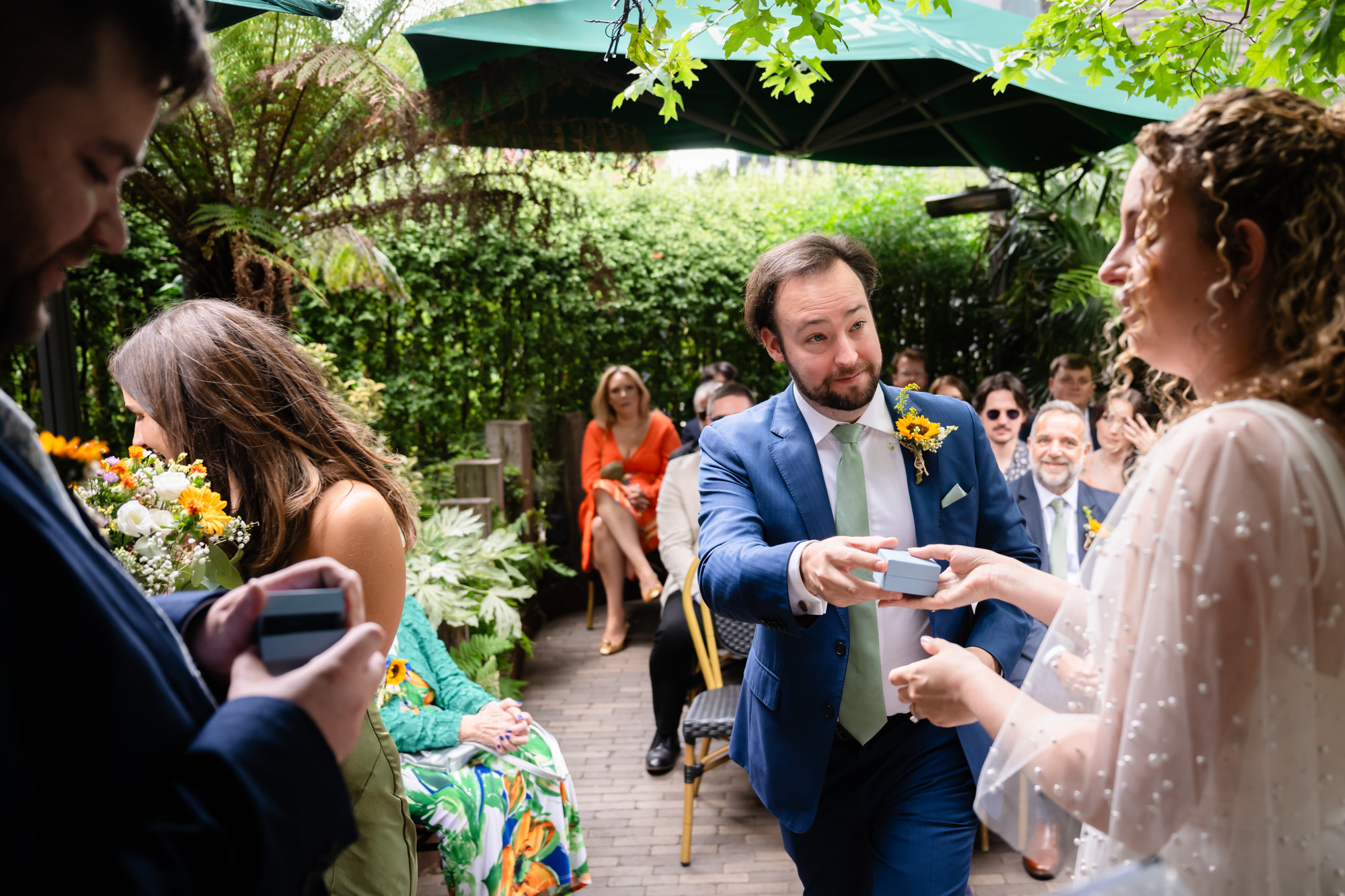 Wedding guest handing over the ring box to the groom during the ceremony