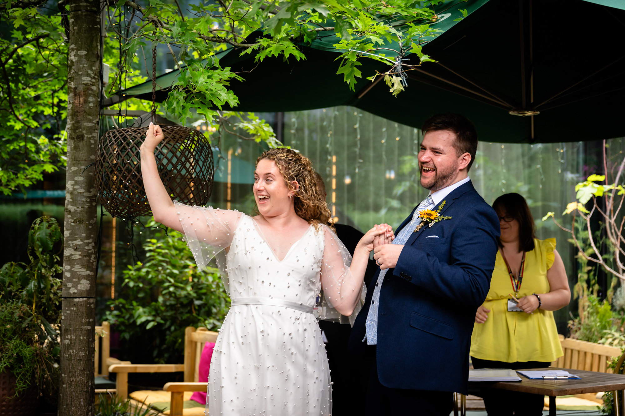 Bride raising her fist and laughing while holding the groom's hand after the ceremony