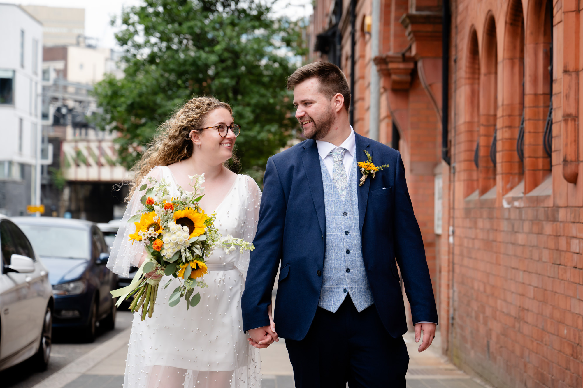 Bride and groom walking along a red-brick street near the Black Friar Salford