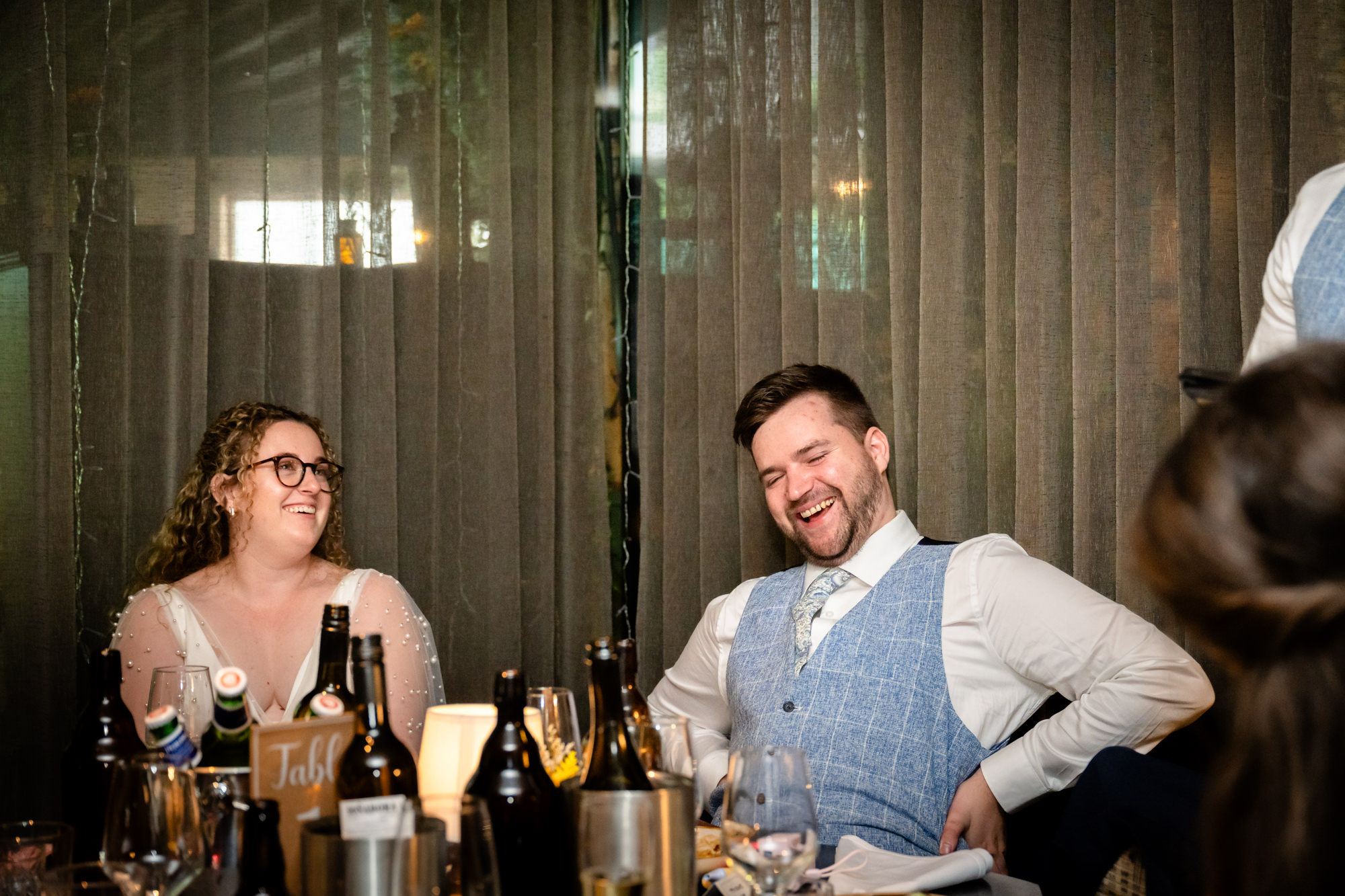Bride and groom laughing together during the wedding speeches
