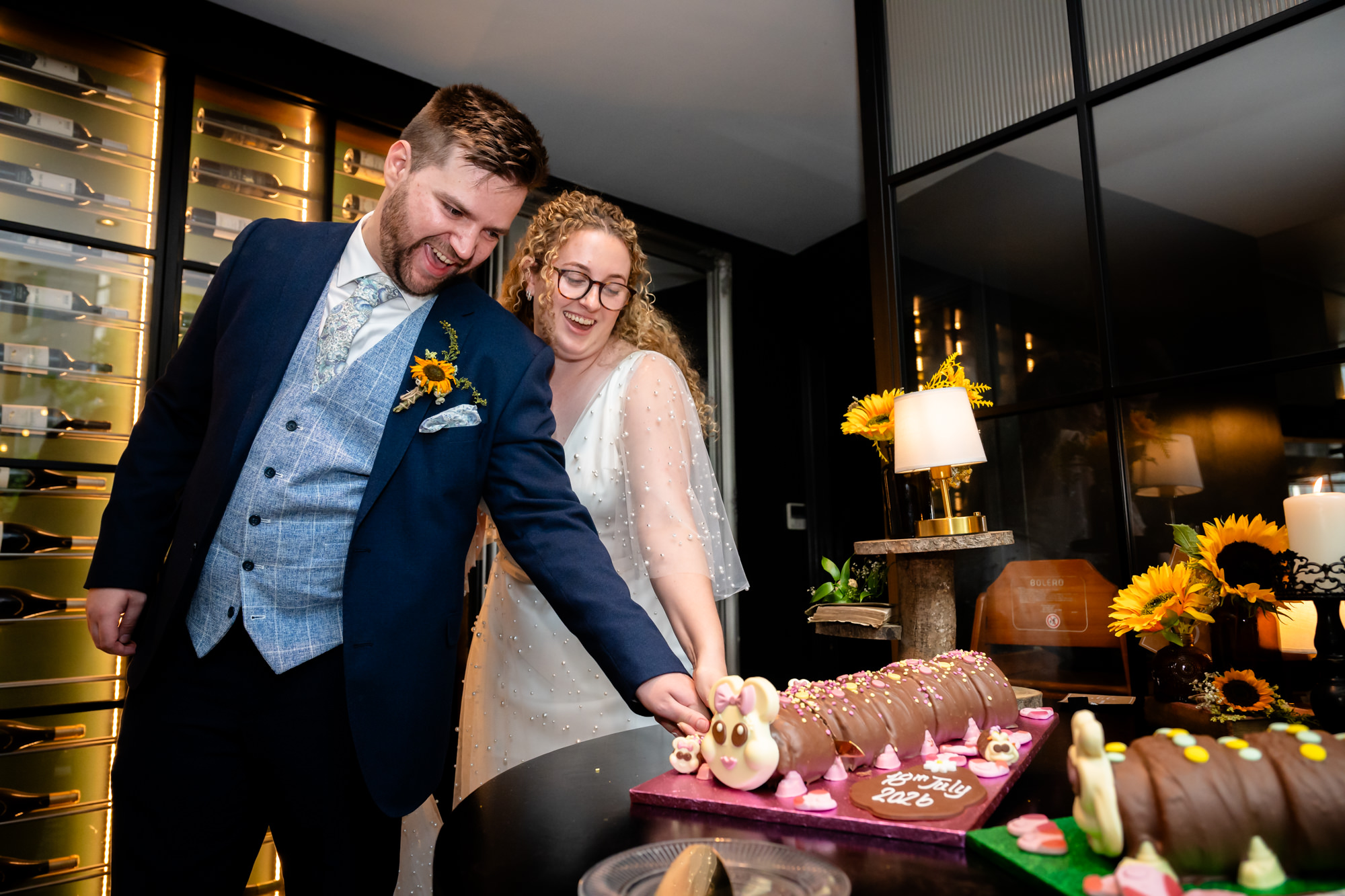 Bride and groom cutting into the chocolate caterpillar cake together