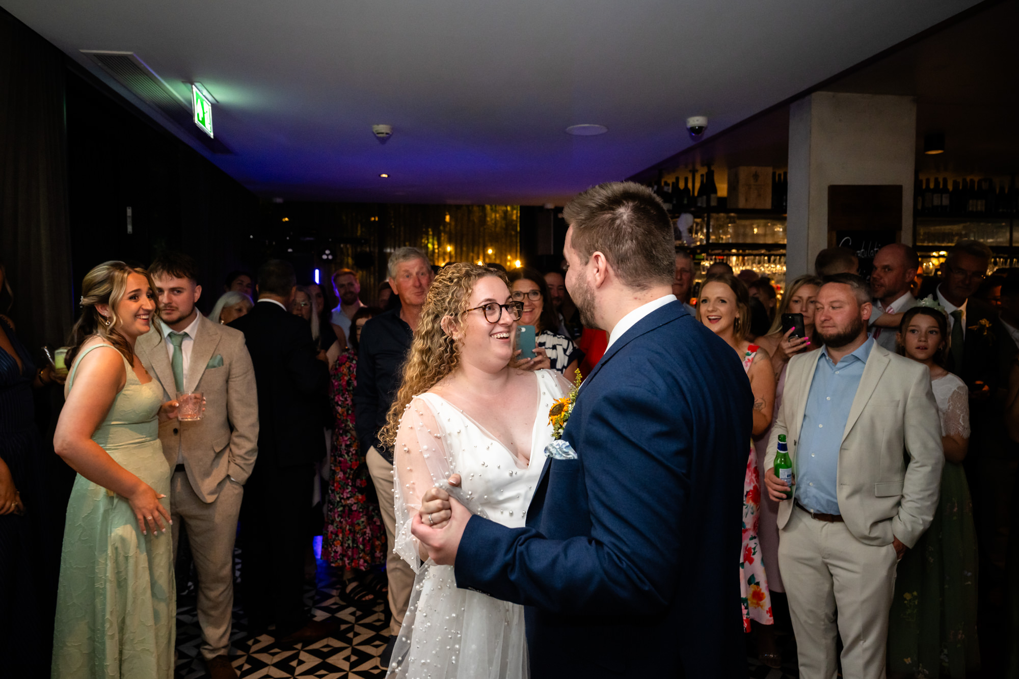Newlyweds sharing their first dance as guests watch and take photos