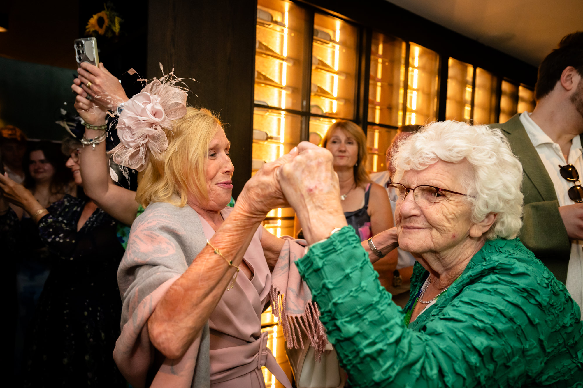 Two wedding guests dancing together, holding hands
