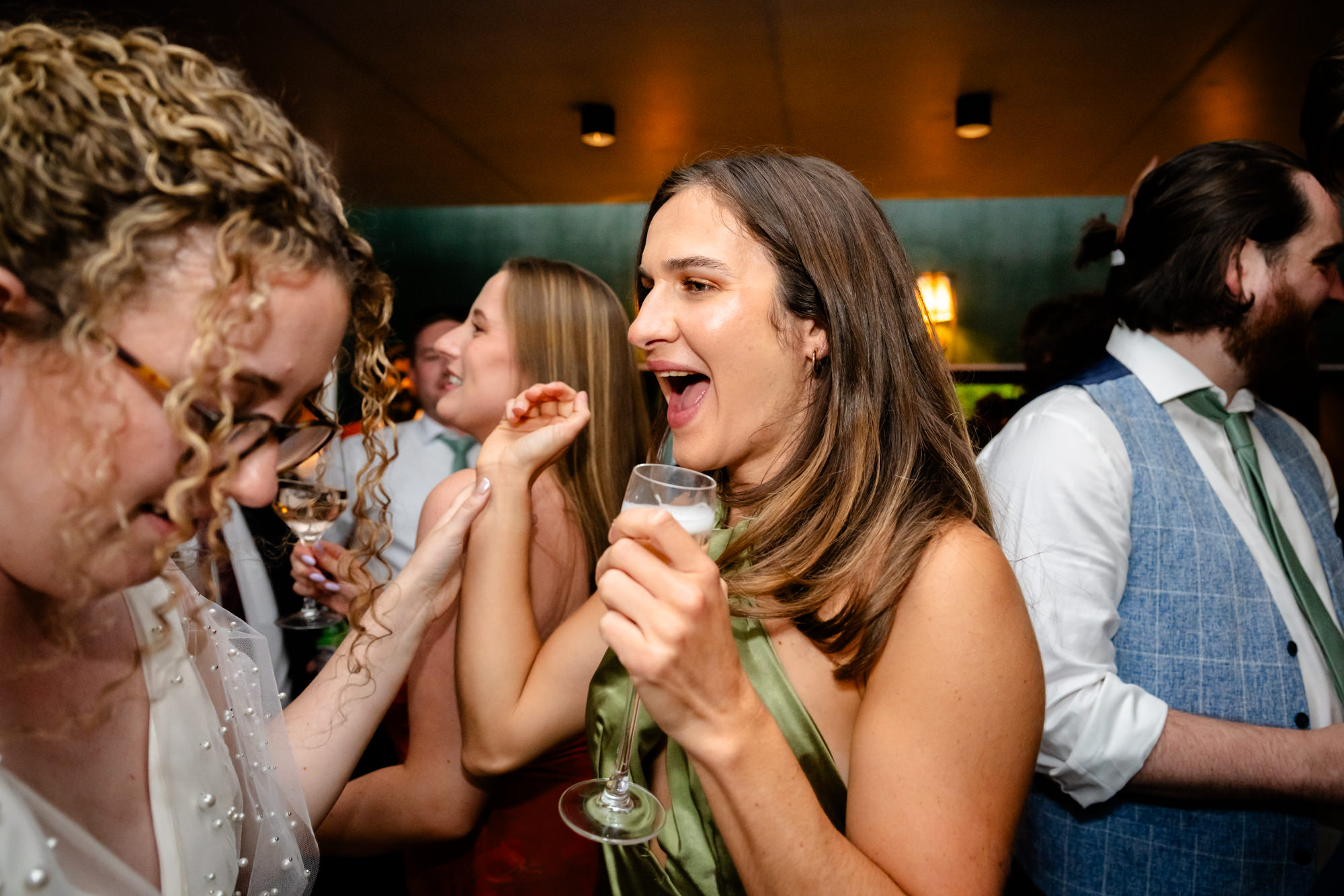 Two wedding guests dancing together, one taking a selfie