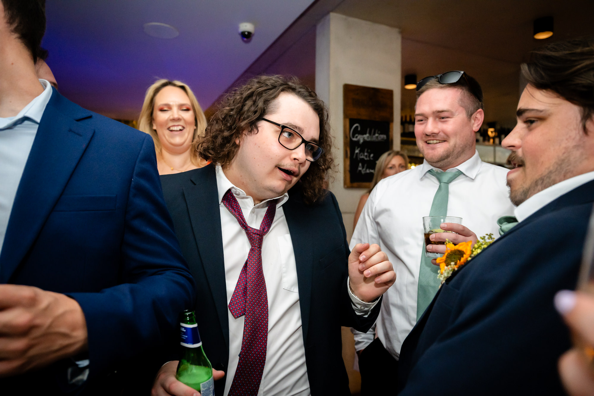 Wedding guests dancing together, pulling faces, drinks in hand