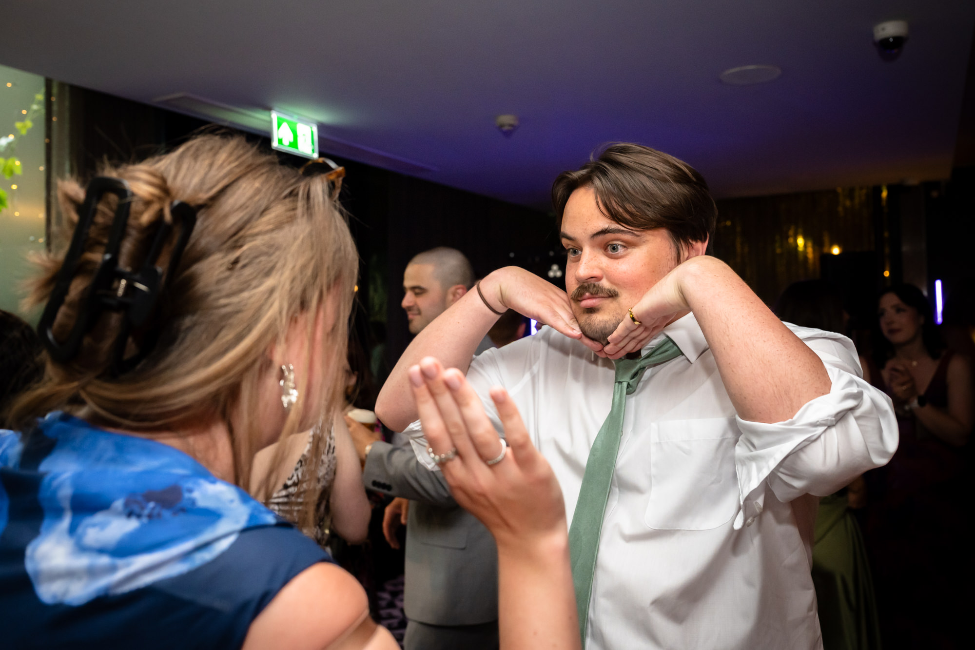Wedding guest pulling a funny face while dancing, hands under his chin