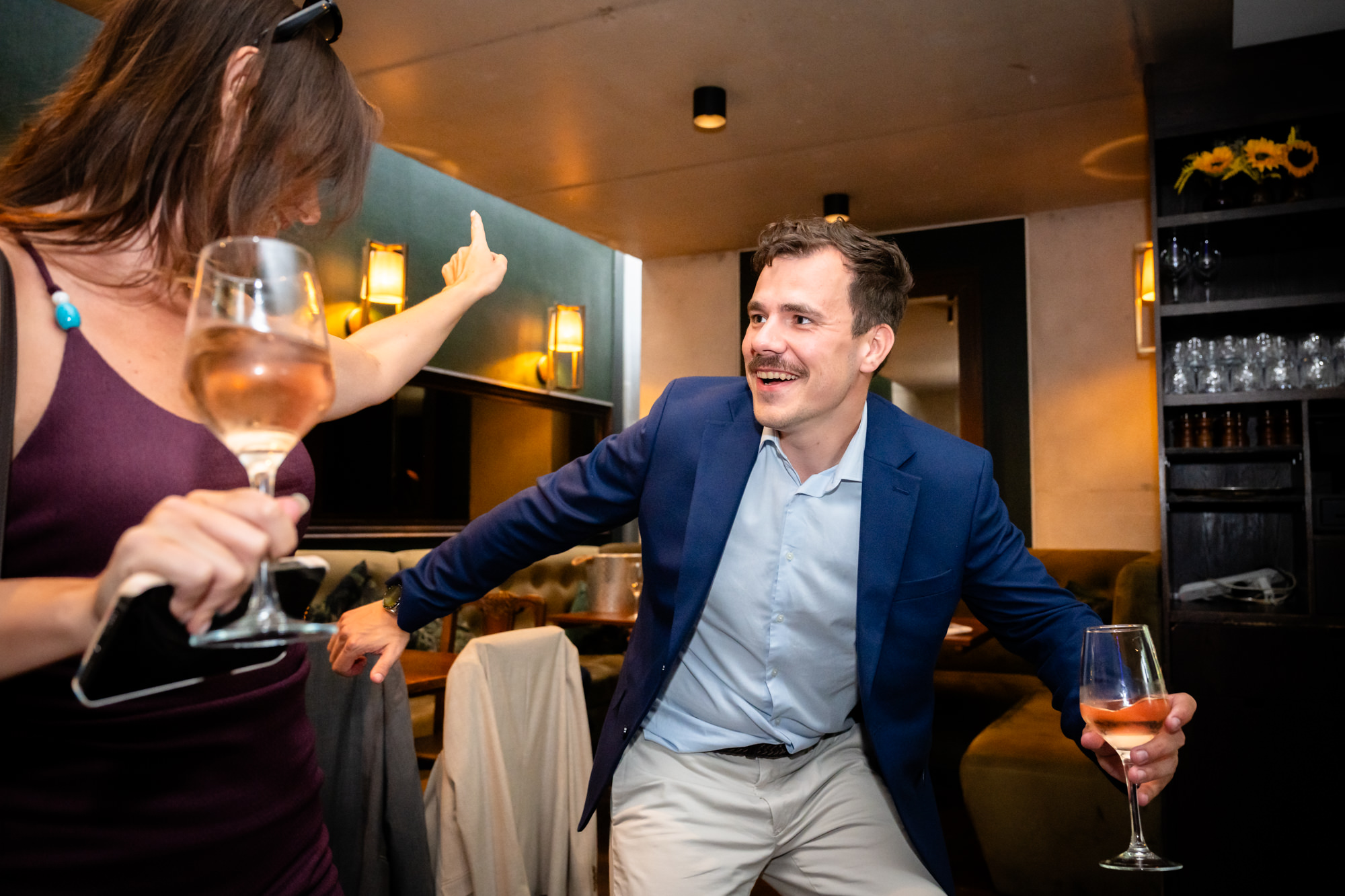 Wedding guest laughing and dancing with a wine glass in hand