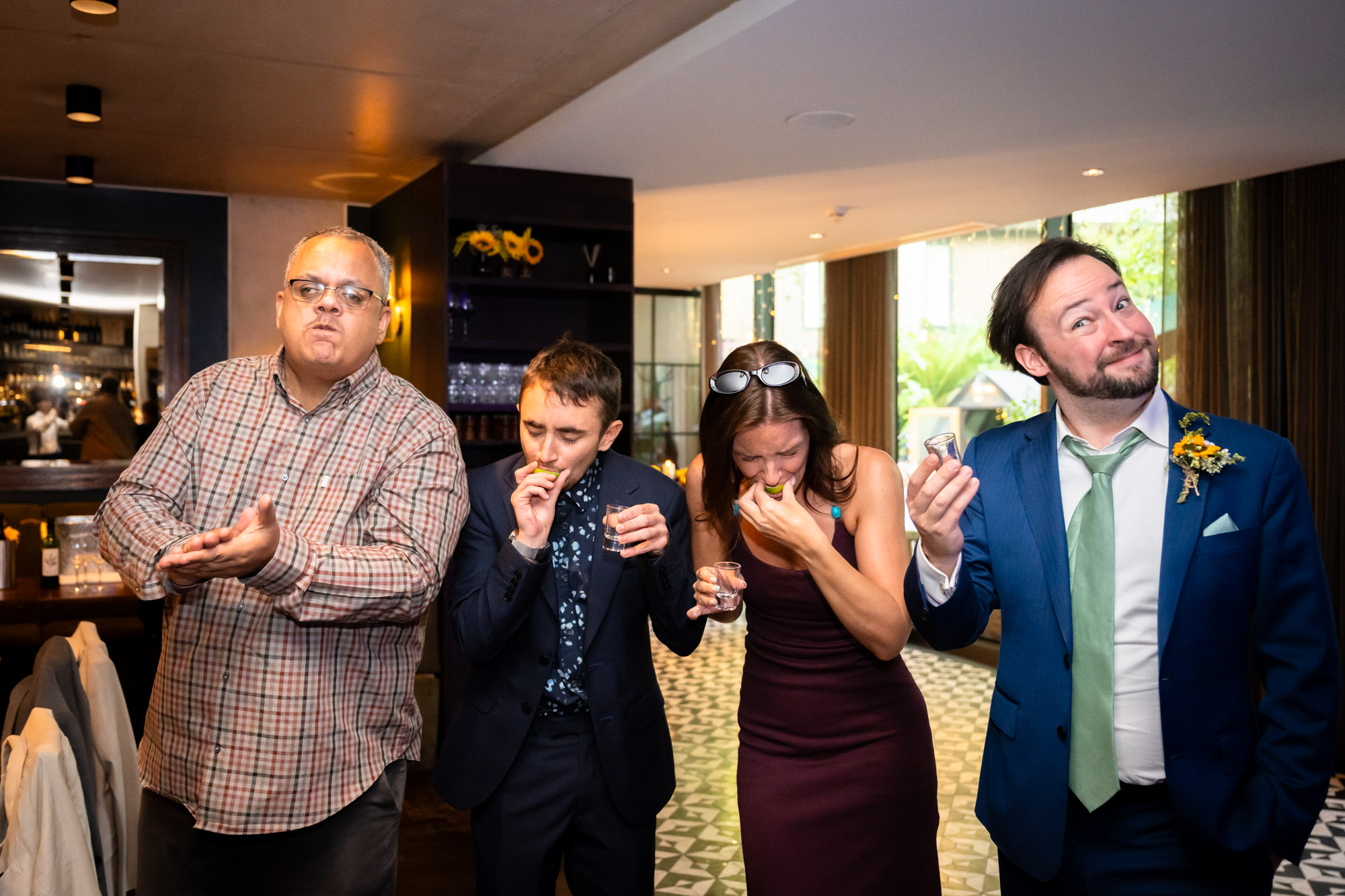 Wedding guests taking tequila shots together, pulling faces