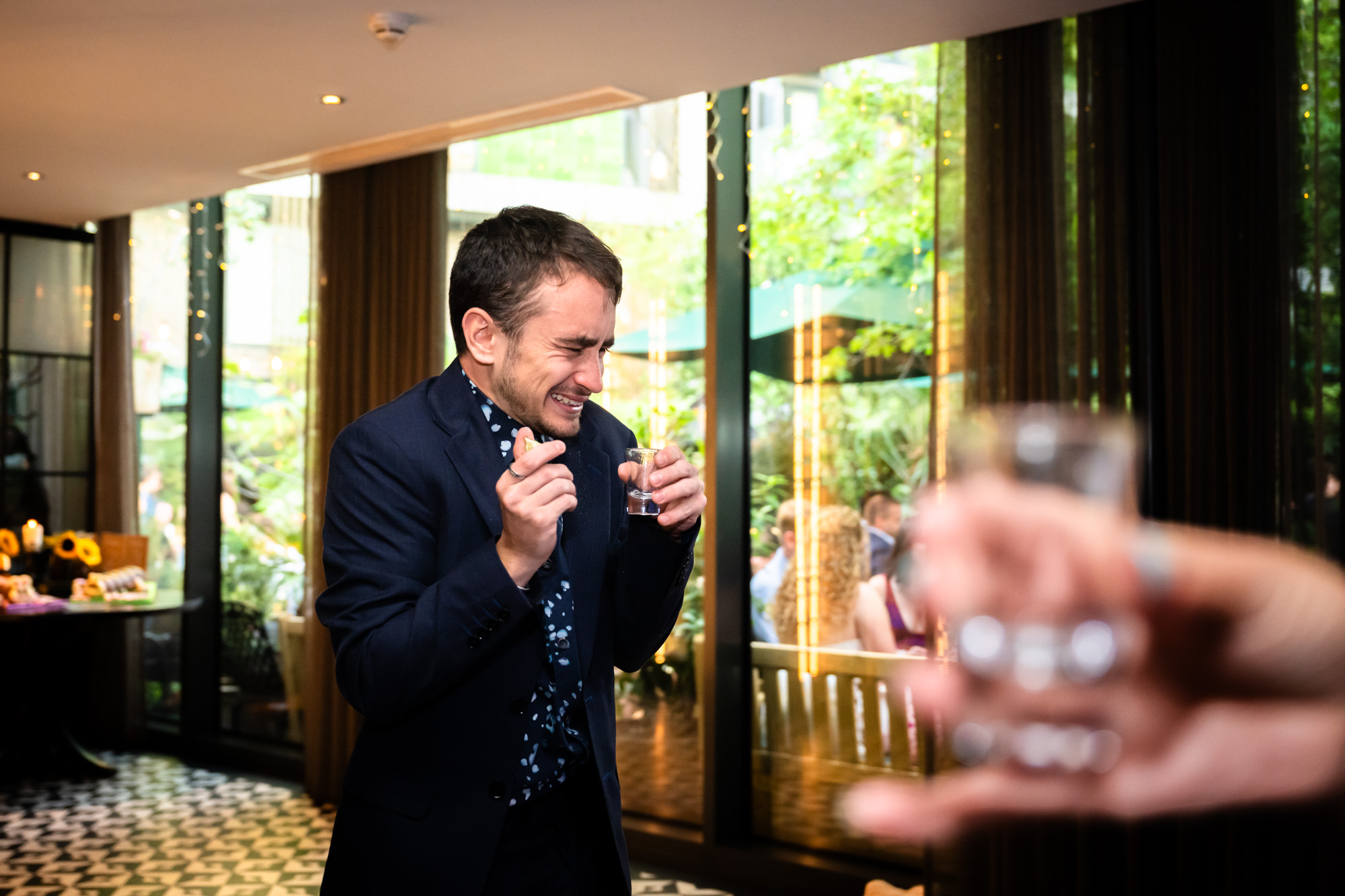Wedding guest pulling a face after drinking a shot