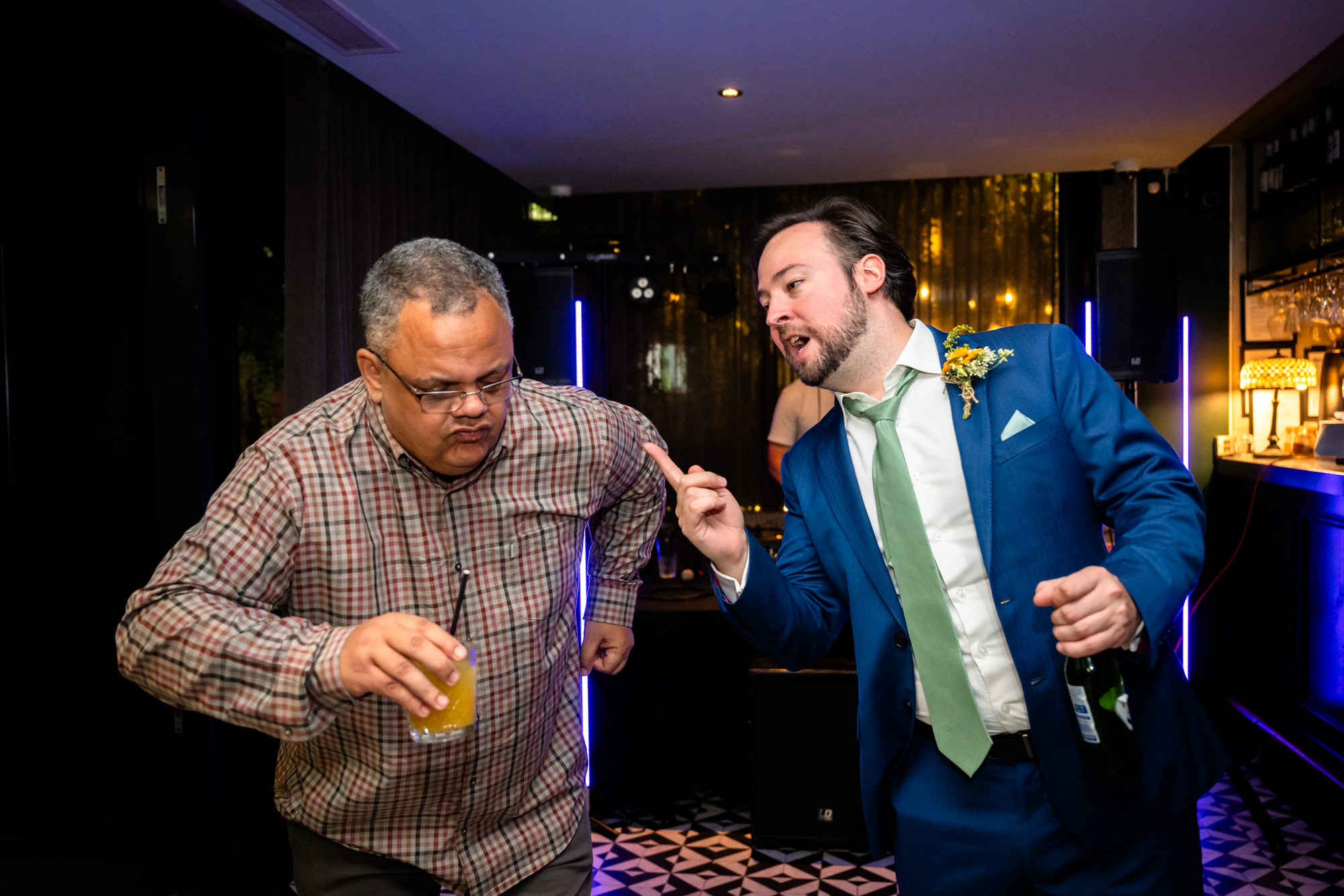 Two wedding guests dancing, one pointing and laughing