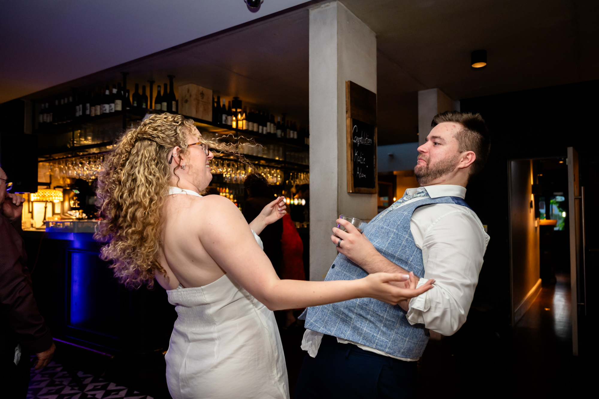 Bride and groom dancing together, groom pulling a funny face