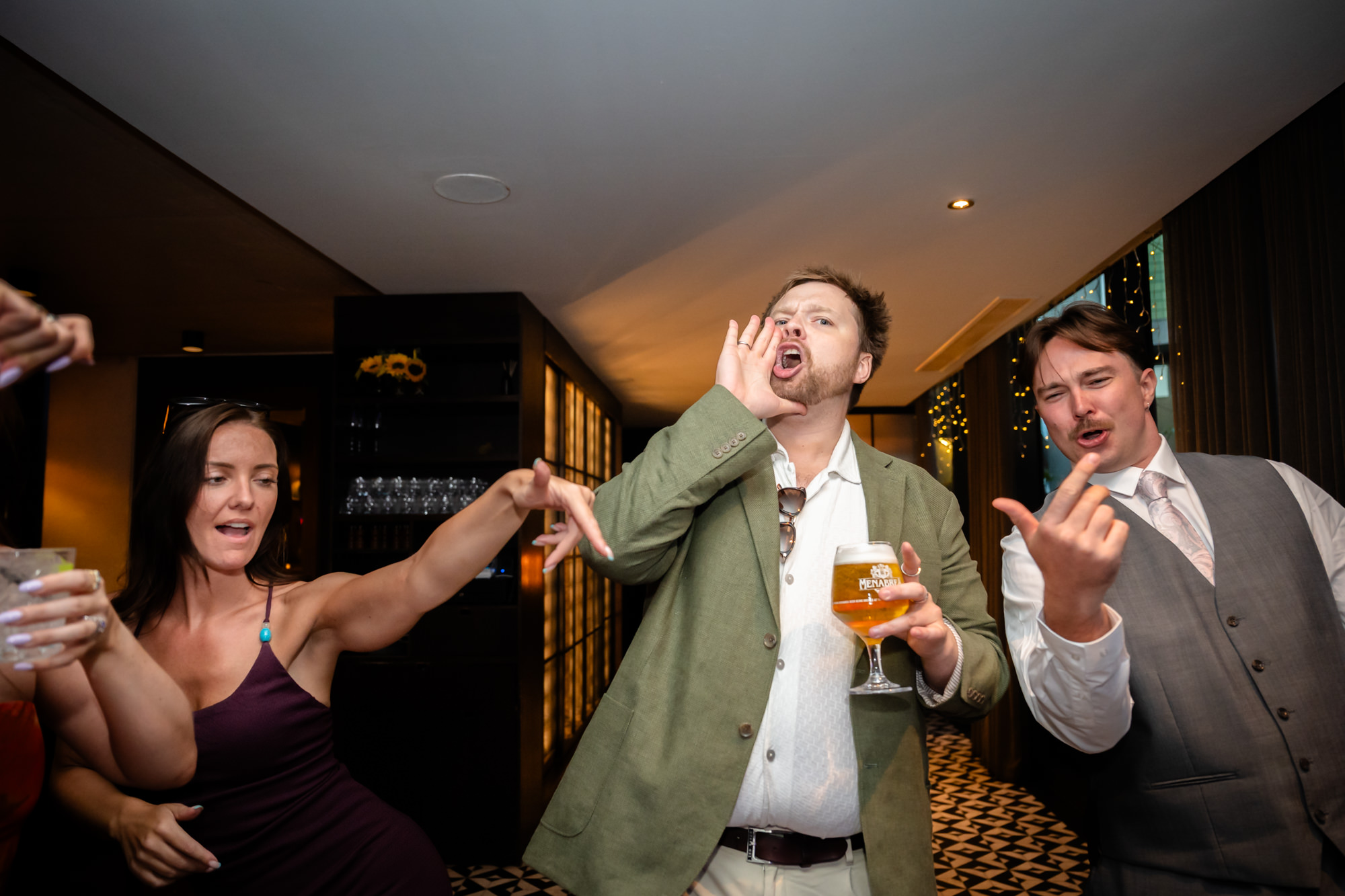 Wedding guest shouting and dancing with friends, drink in hand
