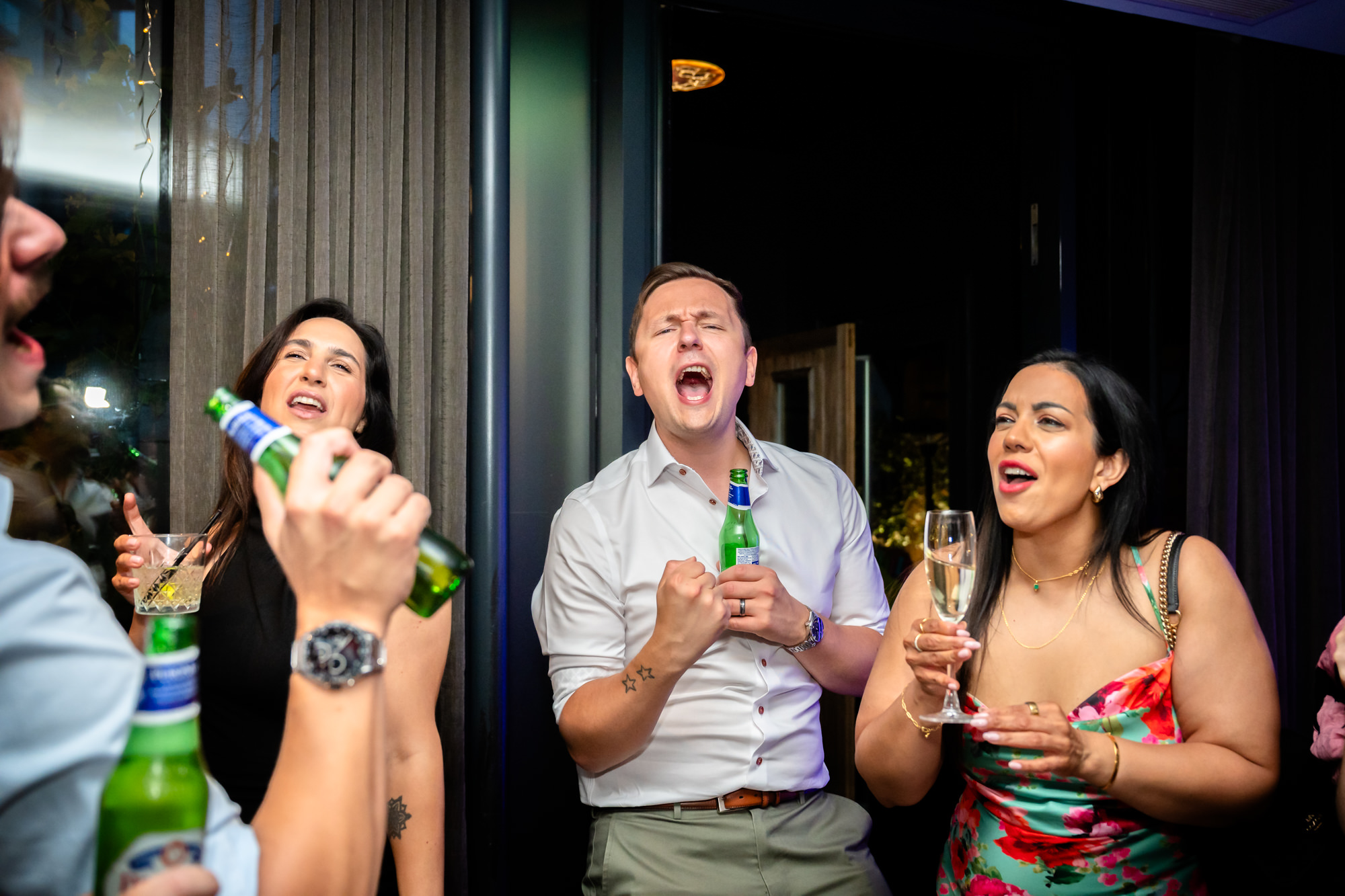 Wedding guests singing and dancing together with drinks in hand